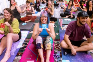 A diverse group enjoys a fun yoga session, smiling with colorful mats and props.