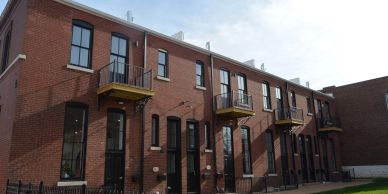 Red brick apartment building with balconies and black window frames.