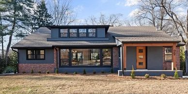 Modern single-story house with large windows and a mix of brick and gray exterior.