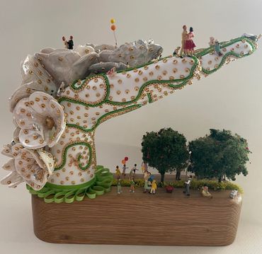 Mannequin hand embellished with beads, ceramic flowers, miniature people, trees, animals and ribbon.