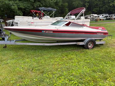 A red and white speedboat on a trailer parked on grass.