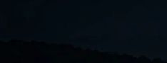 Nighttime mountain silhouette under a dark sky.