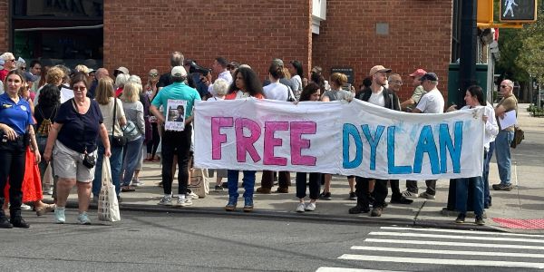 People holding a banner that says 'FREE DYLAN' in a street protest.