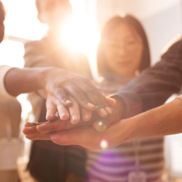 Diverse hands stacked together symbolizing unity and teamwork.