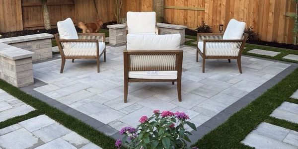 Outdoor patio with four cushioned chairs and stone benches.