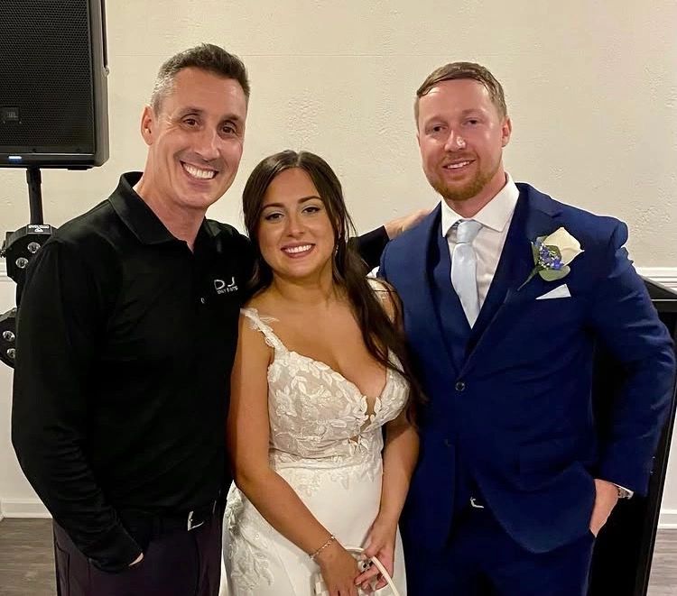 Smiling couple and DJ at wedding.
