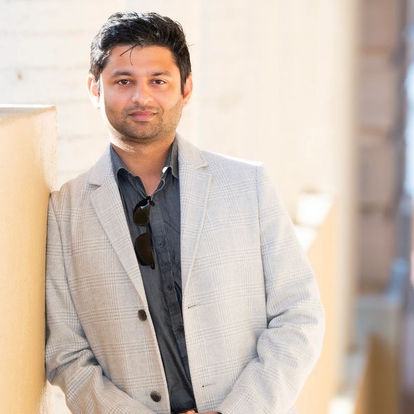 Man leaning against a wall, smiling.