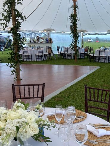 Elegant outdoor wedding reception setup with white flowers and wooden chairs.