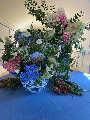 A vibrant floral arrangement in a blue and white vase on a blue tablecloth.