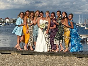 Bride with bridesmaids posing on a dock by the water.