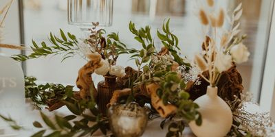 Elegant table centerpiece with greenery and decorative vases.