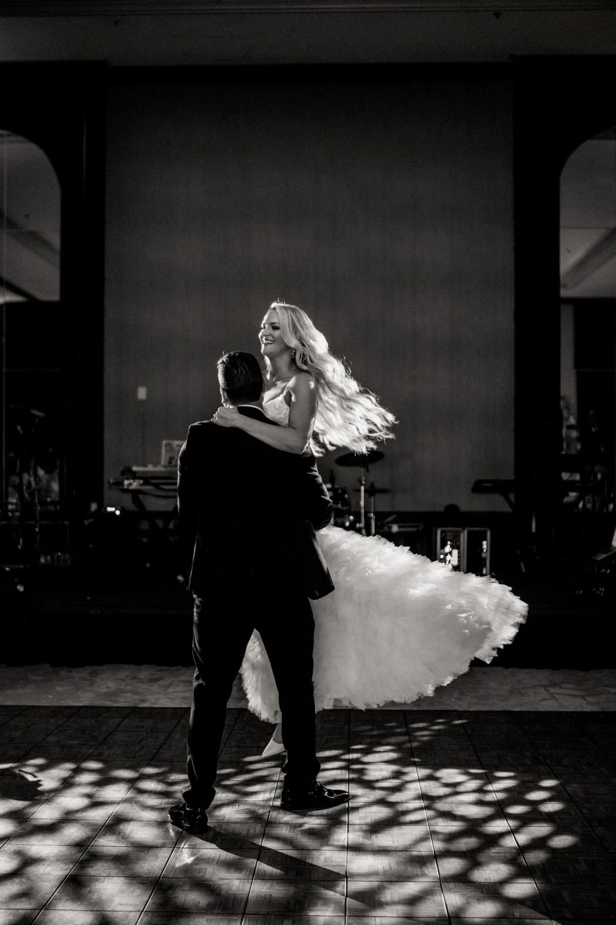 Couple dancing with the bride's dress flowing beautifully in black and white.