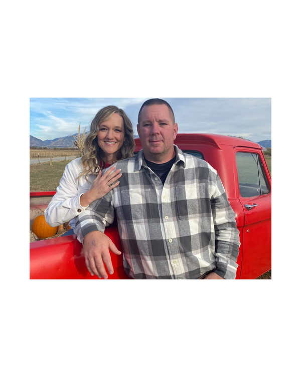 Couple posing by a red vintage truck with pumpkins in the back.