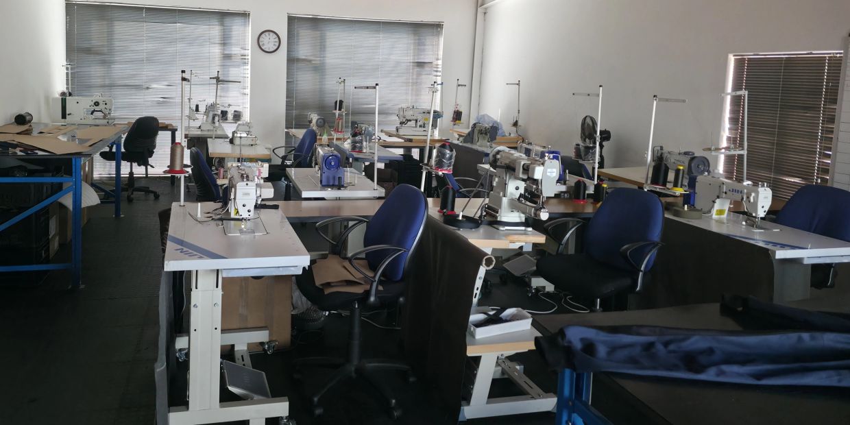 Empty sewing workshop with multiple machines and chairs.
