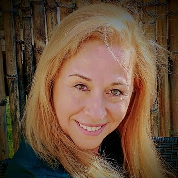 Smiling woman with blonde hair in a natural bamboo background.
