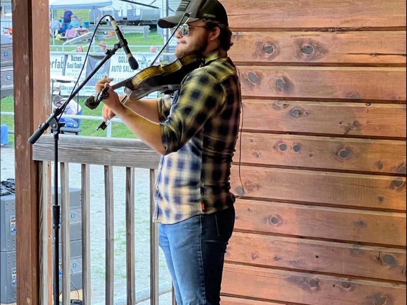 Man playing violin on a wooden stage.
