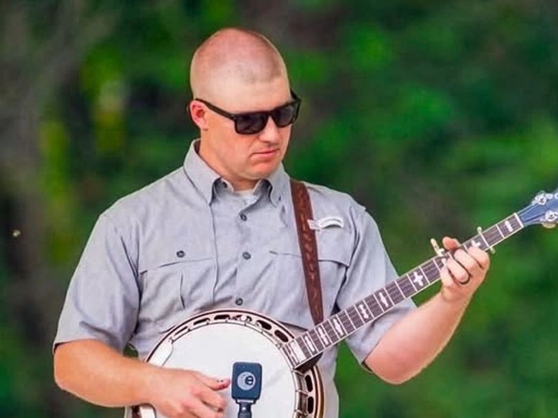 Man playing a banjo outdoors.