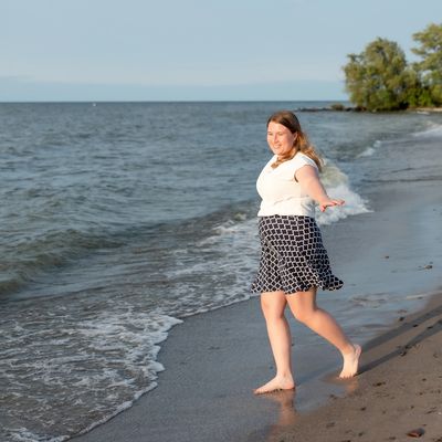 Woman walking barefoot on the beach with a smile.