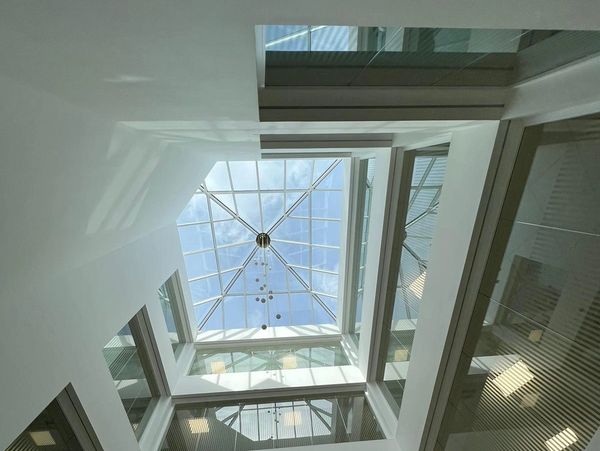 Modern building atrium with glass ceiling and chandelier.