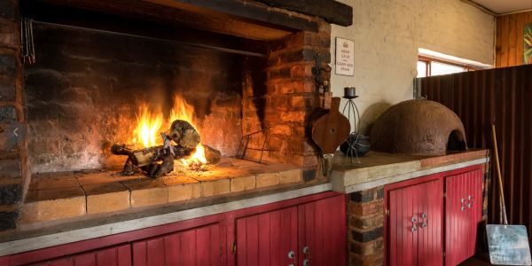 Cozy indoor fireplace with burning firewood and red cabinets.