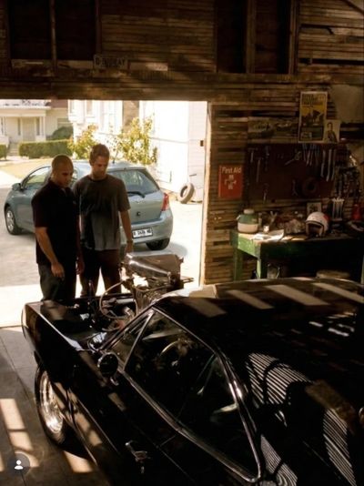 Two men inspecting a black car in a garage.