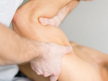 Therapist performing a shoulder massage on a client.