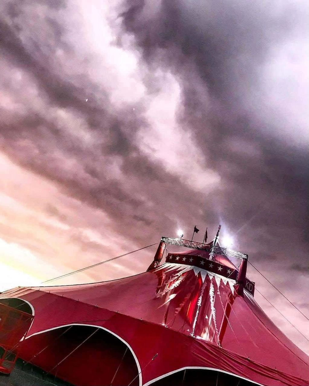 Dramatic red circus tent under a moody, cloudy sky.
