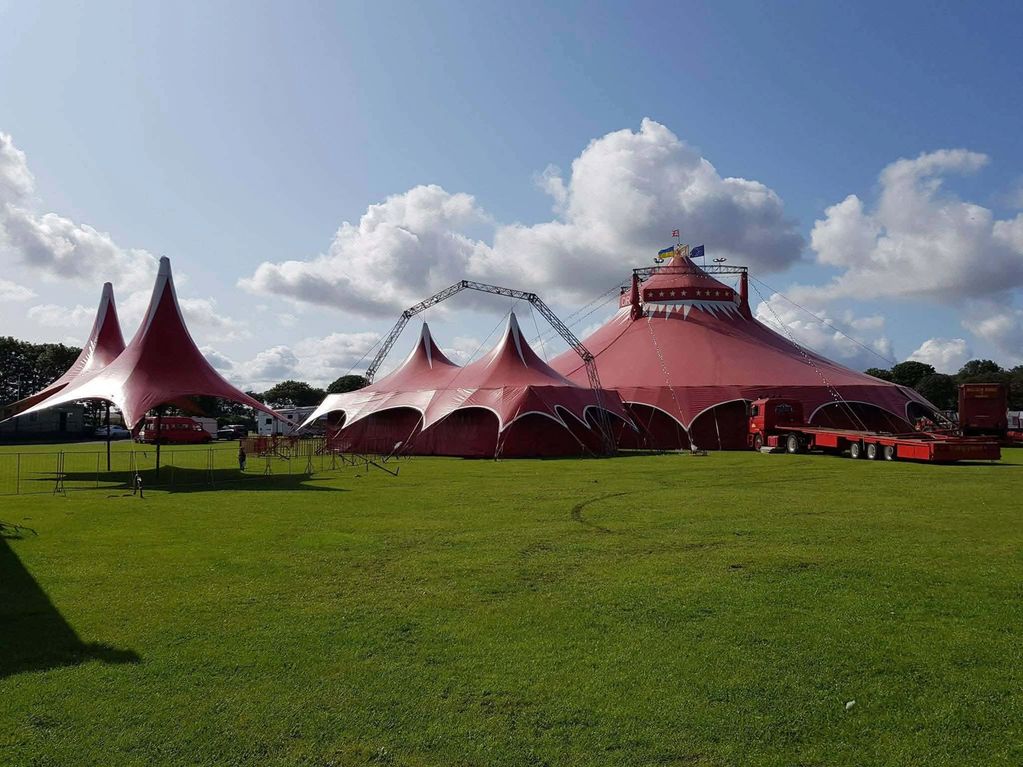 A large red circus tent set up on a grassy field.