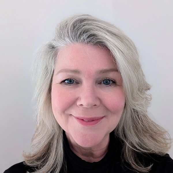 Smiling middle-aged woman with gray hair and blue eyes.