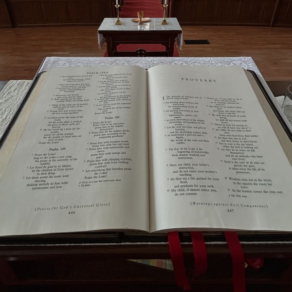 Open Bible on a church altar with red ribbons and candles.