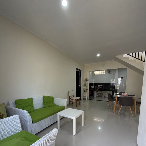 Modern living room with white wicker furniture and green cushions.