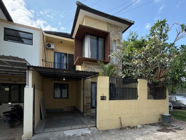 Modern two-story house with a carport and small garden.