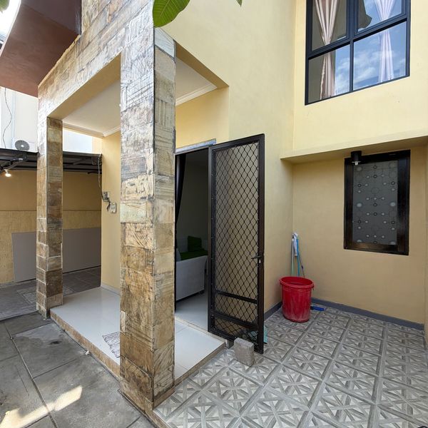 Modern porch with tiled pillars, open door, and cleaning tools.