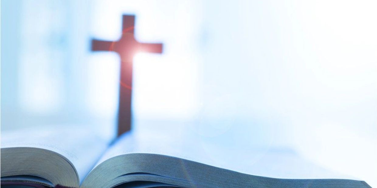 Open Bible with a glowing cross in the background symbolizing faith.