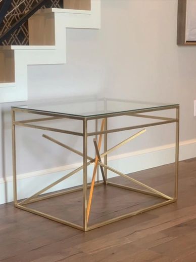 Wrought iron starburst accent table with gold finish and glass top. 