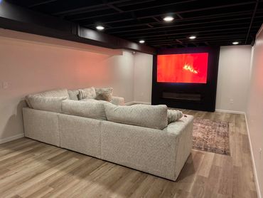 Cozy modern basement with large beige sectional and glowing TV.