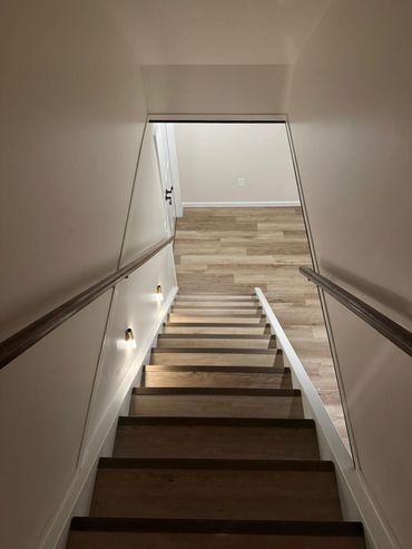 Modern wooden staircase with wall lights and handrails.