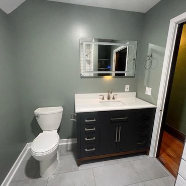 Modern bathroom with a sleek vanity and toilet against gray walls.