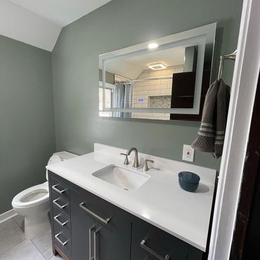 Modern bathroom with a sleek vanity, mirror, and toilet.