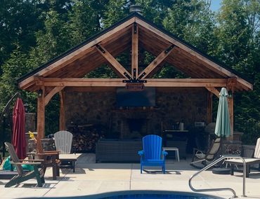 A cozy wooden pavilion with chairs and umbrellas by a pool.