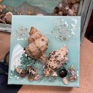 Resin on a 6”x 6” canvas block with coastal items of shells and broken glass.