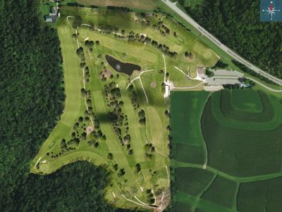 Aerial view of a golf course surrounded by forests and farmland.