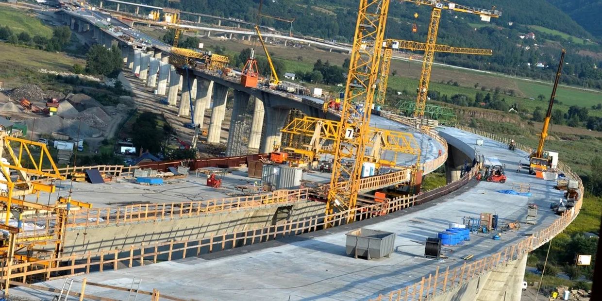 Large bridge under construction with cranes and equipment.