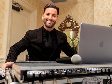 Smiling DJ in black attire with equipment.