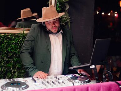 DJ wearing a hat playing music at a party.