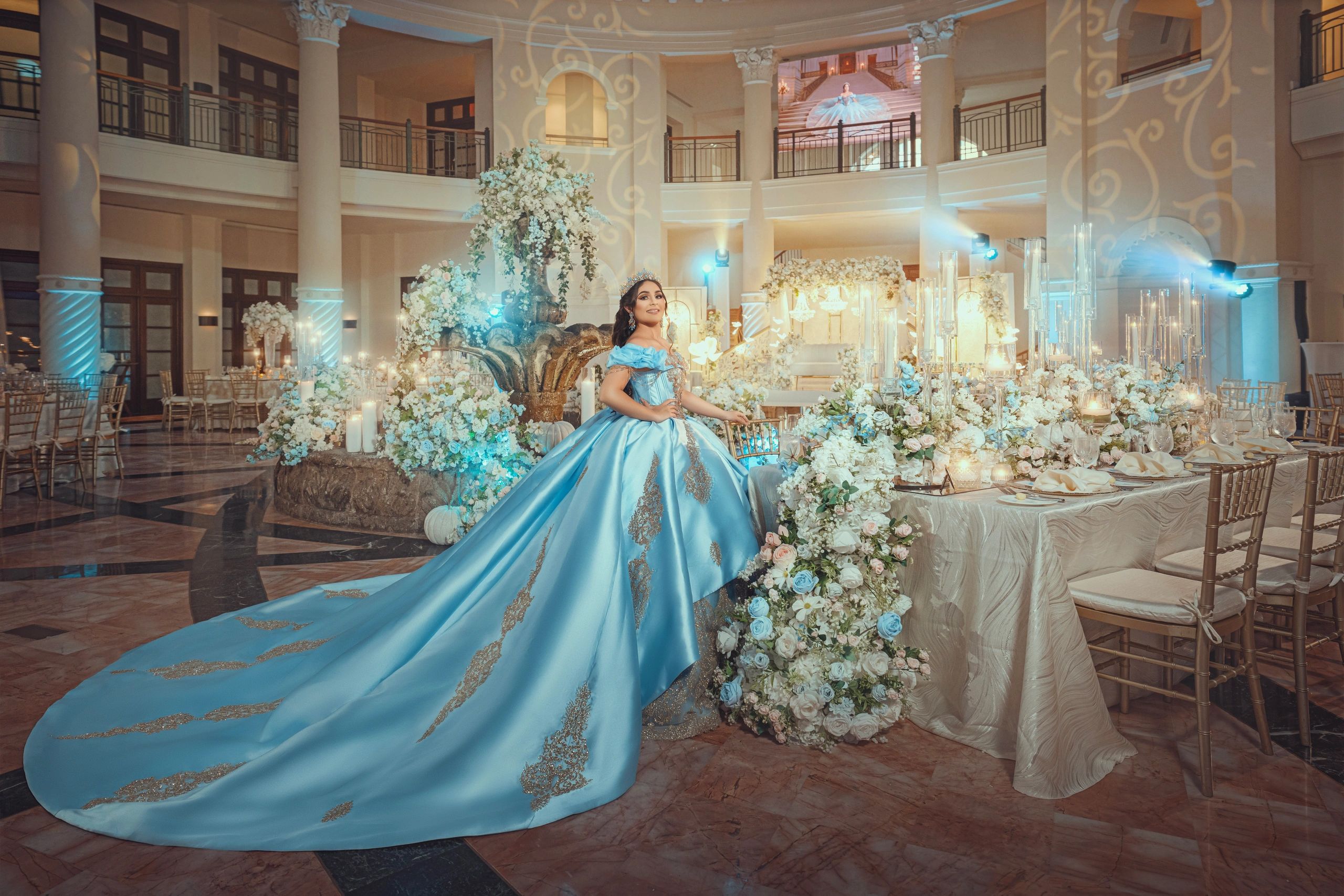 Woman in a blue gown at a lavishly decorated event.