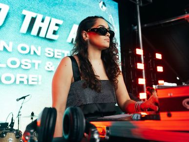 Woman DJ wearing sunglasses at a music event.
