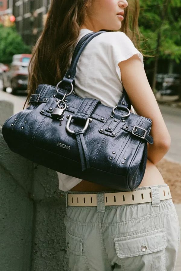 Woman carrying a black leather handbag over her shoulder.