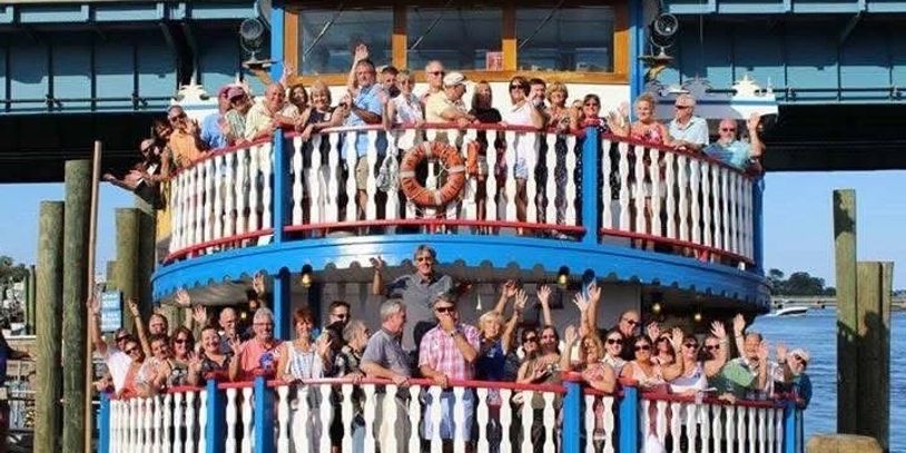 Group photo on a two-level boat with people waving.