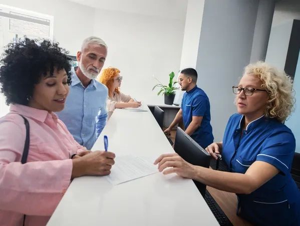 Elderly couple signing document at medical reception.